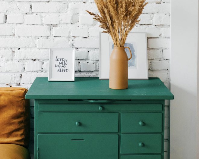 Modern green drawer cabinet with framed art and vase on top